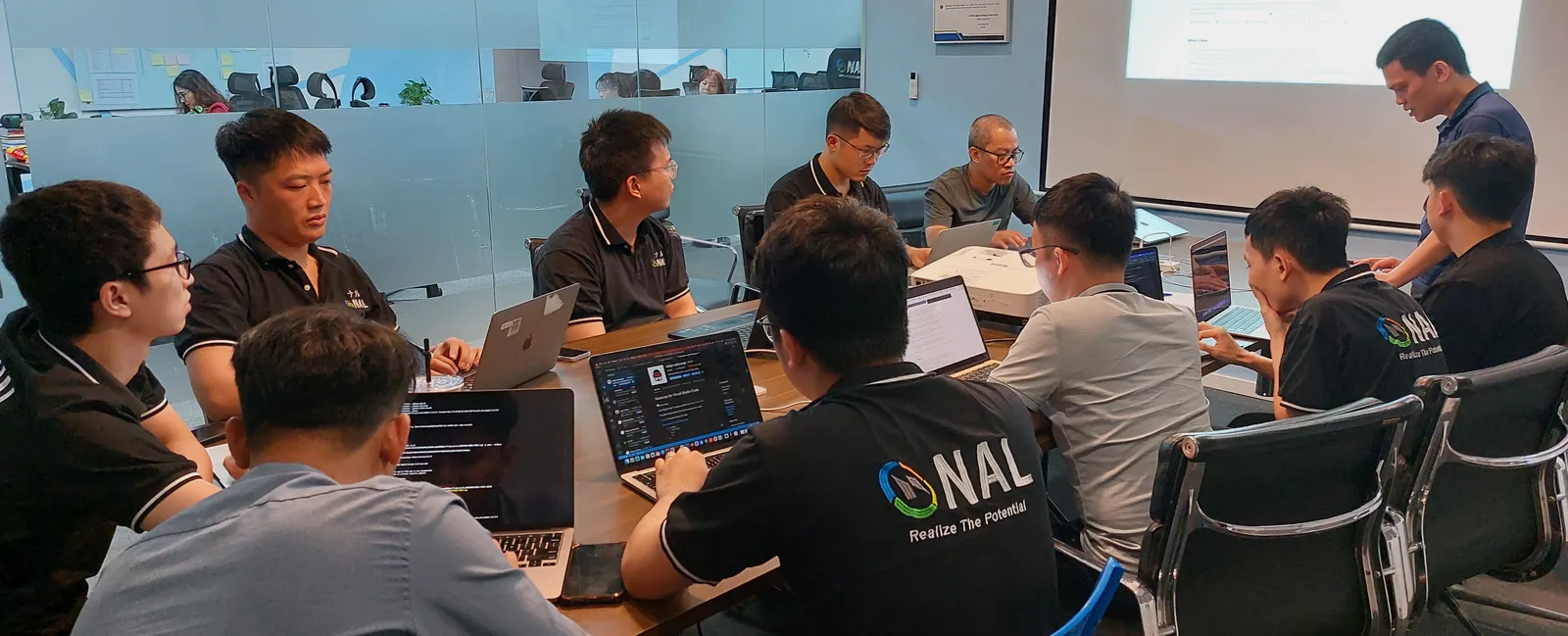 会議室のテーブルを囲み、ノートパソコンで開発を進めるNALのエンジニアたち