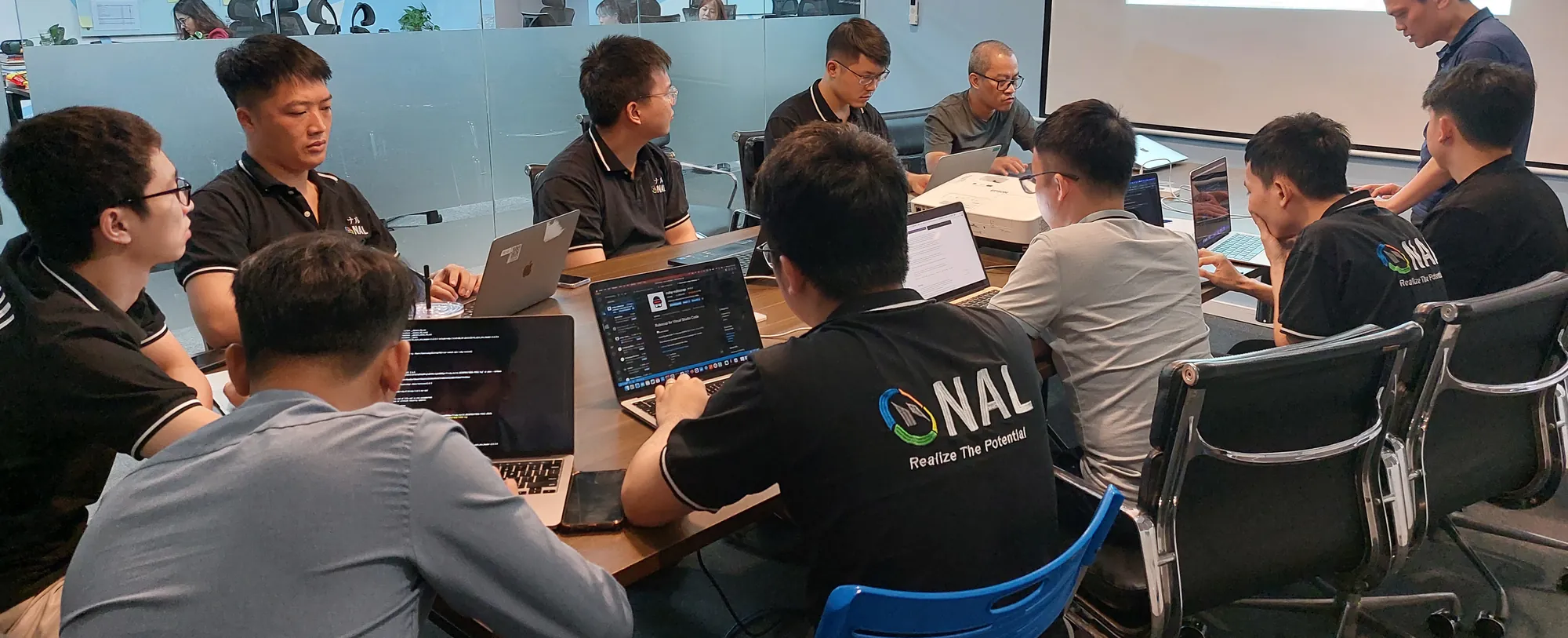 ノートパソコンを開いて打ち合わせをする、NALのメンバー